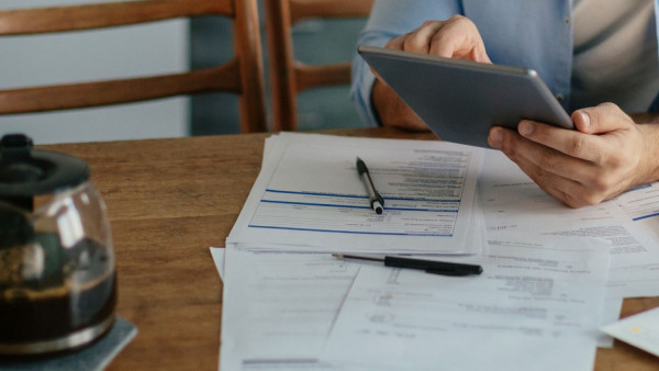 Person sits at a table reviewing bills.